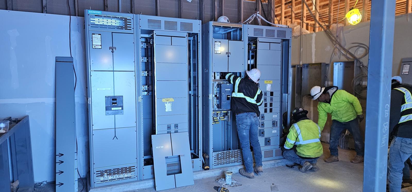 Electricians working at large distribution equipment on a construction site