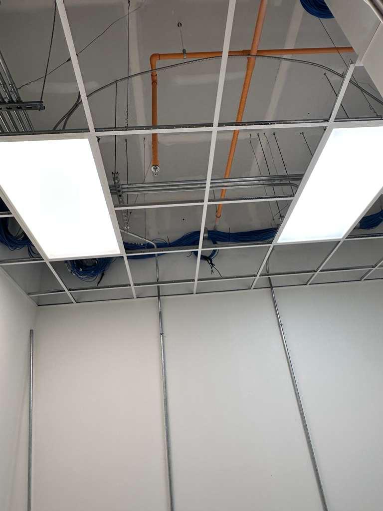 Two illuminated panels in an open commercial ceiling under construction